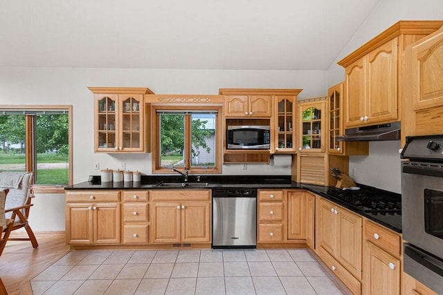 kitchen featuring sink, vaulted ceiling, dark stone countertops, light hardwood / wood-style floors, and stainless steel appliances