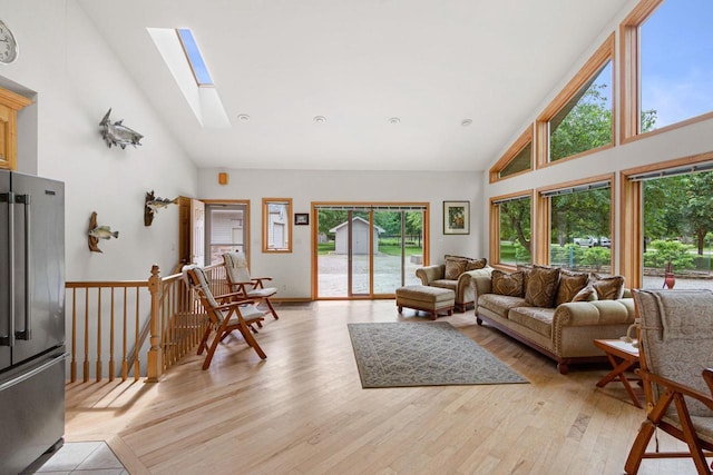 living room featuring a skylight, light hardwood / wood-style flooring, and high vaulted ceiling