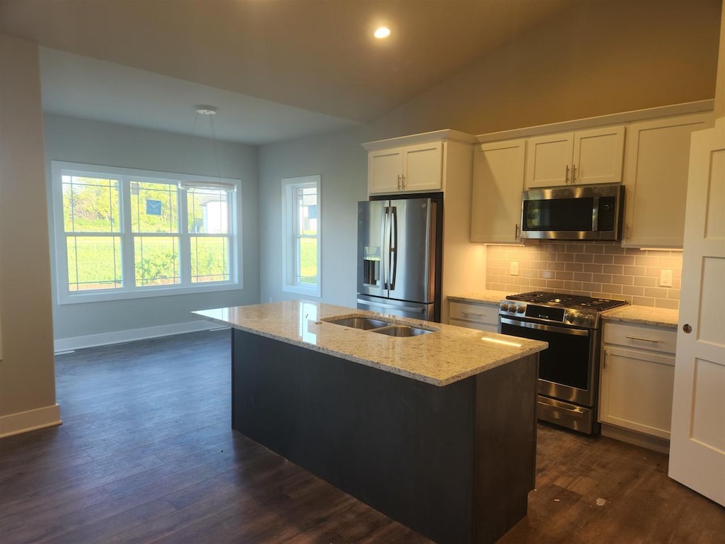 kitchen featuring stainless steel appliances, dark hardwood / wood-style flooring, vaulted ceiling, a kitchen island with sink, and white cabinets