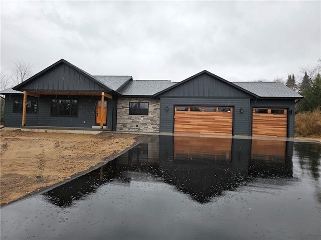 view of front of home with an attached garage, aphalt driveway, and roof with shingles