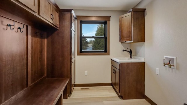 mudroom featuring a sink, light wood-style flooring, and baseboards