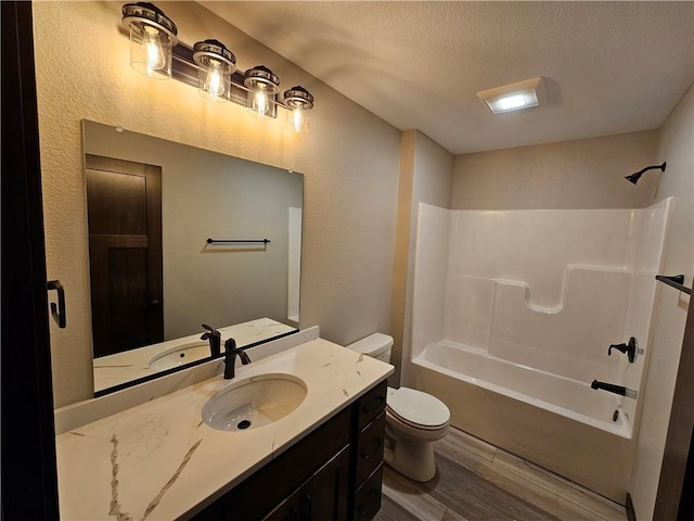 full bathroom with a textured ceiling, shower / bathing tub combination, wood-type flooring, vanity, and toilet