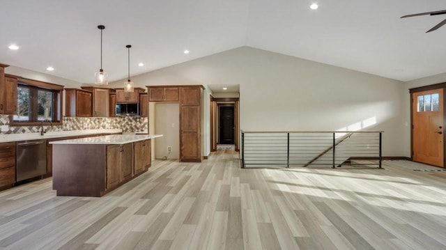 kitchen featuring pendant lighting, appliances with stainless steel finishes, brown cabinetry, a kitchen island, and vaulted ceiling