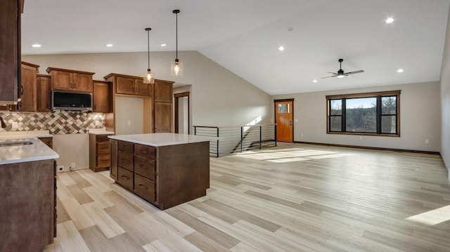 kitchen with open floor plan, light countertops, stainless steel microwave, and a center island