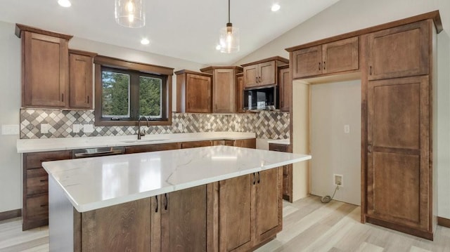 kitchen featuring brown cabinets, pendant lighting, and a sink