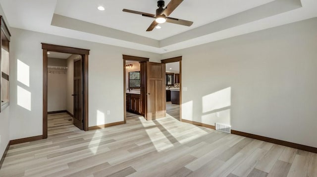 unfurnished room with a raised ceiling, visible vents, light wood finished floors, and baseboards