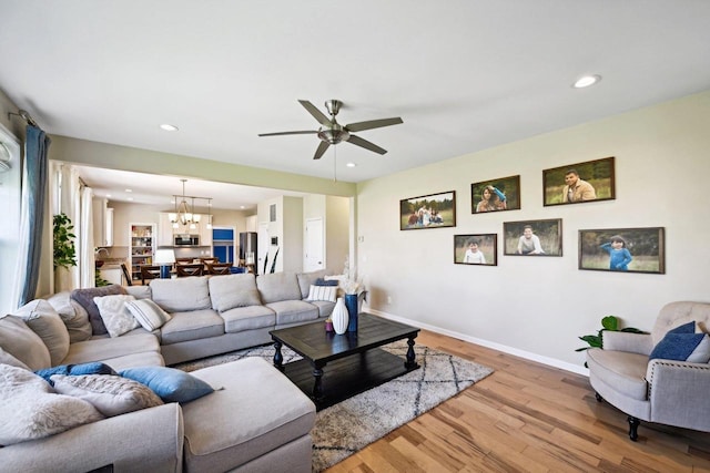 living room with ceiling fan with notable chandelier and light wood-type flooring