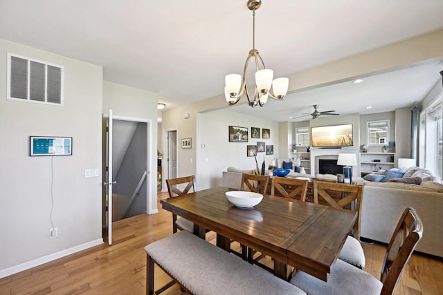 dining area with ceiling fan with notable chandelier and light hardwood / wood-style floors