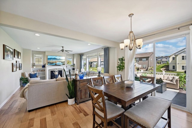 dining room with ceiling fan with notable chandelier and light hardwood / wood-style flooring