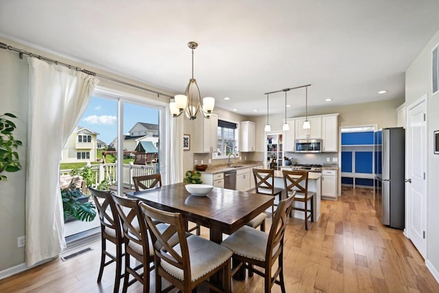 dining space with light hardwood / wood-style floors, sink, and a chandelier