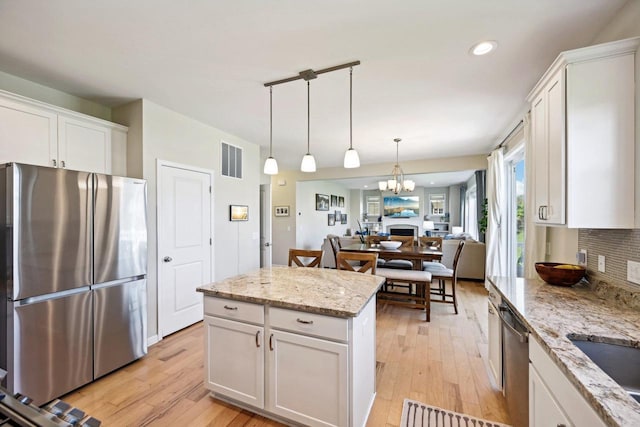 kitchen with backsplash, white cabinetry, light wood-type flooring, and appliances with stainless steel finishes