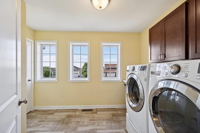 clothes washing area featuring cabinets and separate washer and dryer