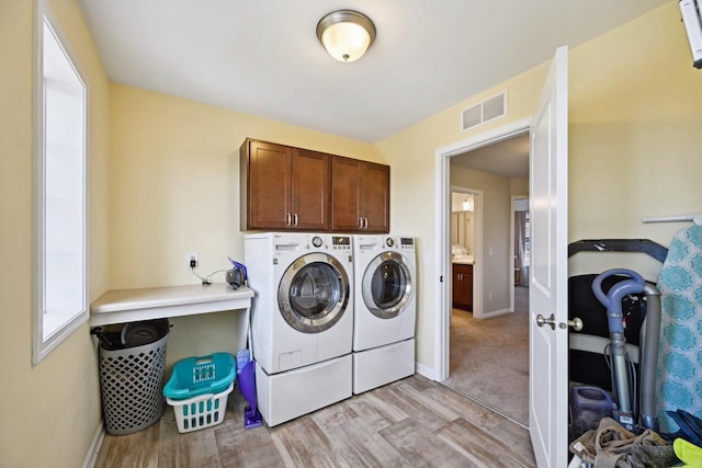 laundry area with washer and dryer, cabinets, and light hardwood / wood-style floors