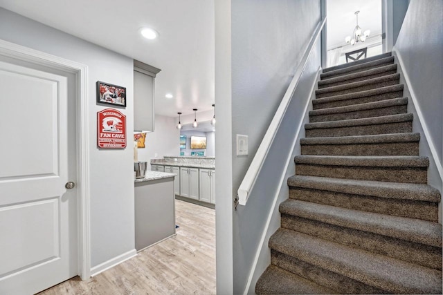 stairway featuring a healthy amount of sunlight, wood-type flooring, and a chandelier