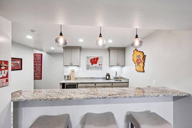 kitchen featuring a breakfast bar, decorative light fixtures, gray cabinets, and kitchen peninsula