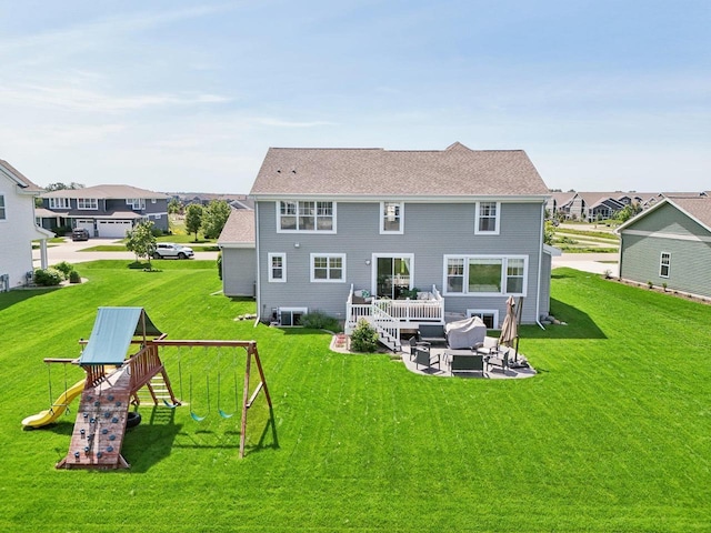 rear view of property featuring a lawn, an outdoor living space, and a playground