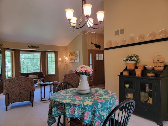 carpeted dining area featuring a chandelier and high vaulted ceiling