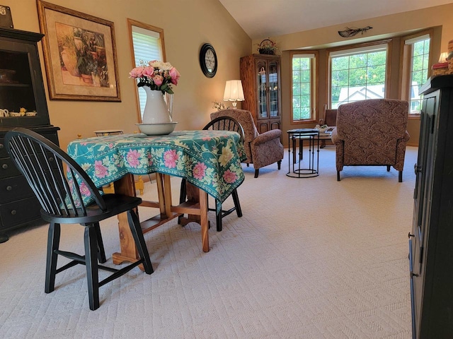 carpeted dining area with vaulted ceiling