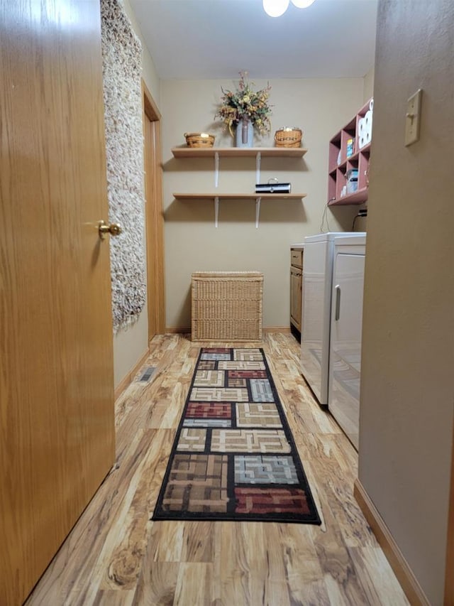 clothes washing area featuring washer and clothes dryer, cabinets, and light wood-type flooring