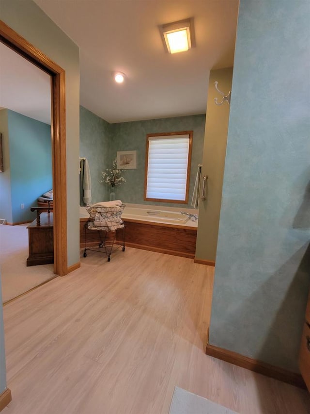 bathroom with a tub to relax in and hardwood / wood-style flooring