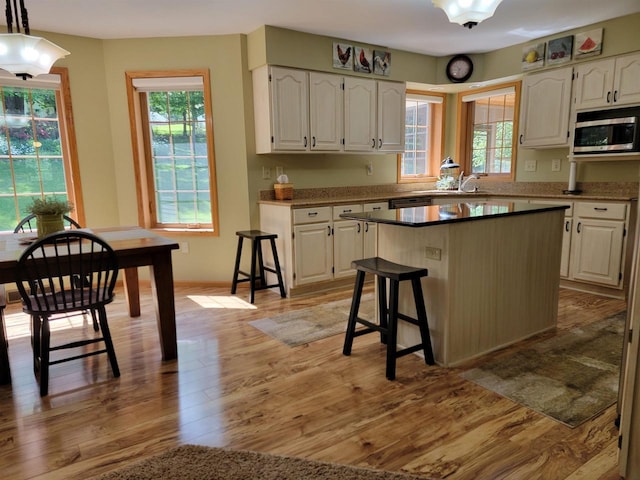 kitchen with white cabinets, a kitchen breakfast bar, light hardwood / wood-style floors, and a kitchen island