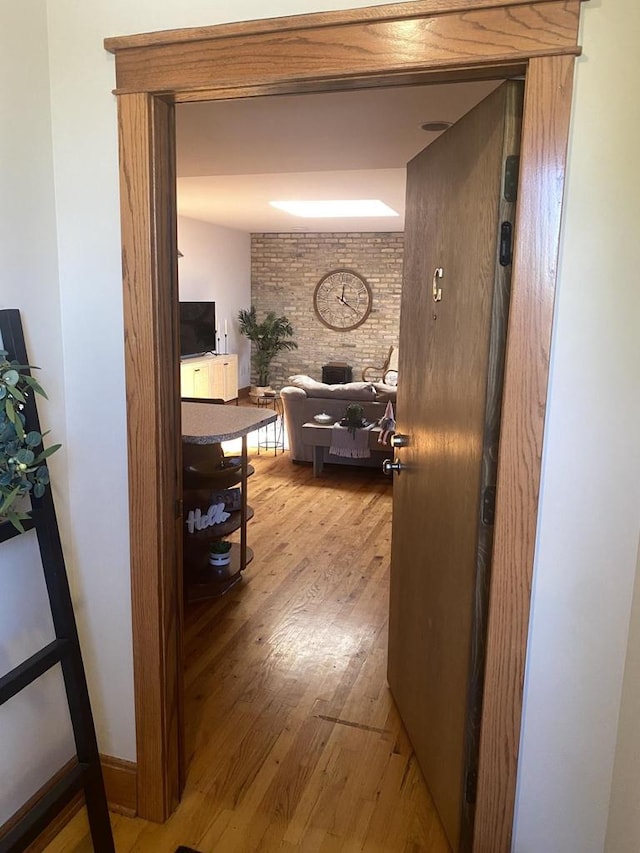 corridor with brick wall and light hardwood / wood-style flooring