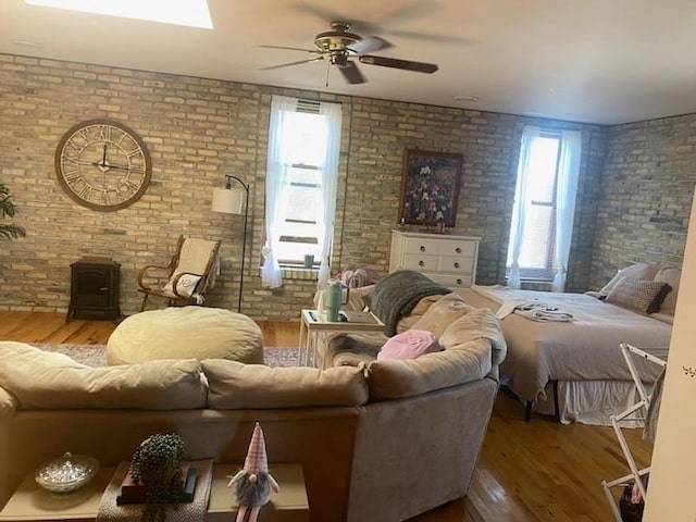 bedroom with ceiling fan, light wood-type flooring, and brick wall