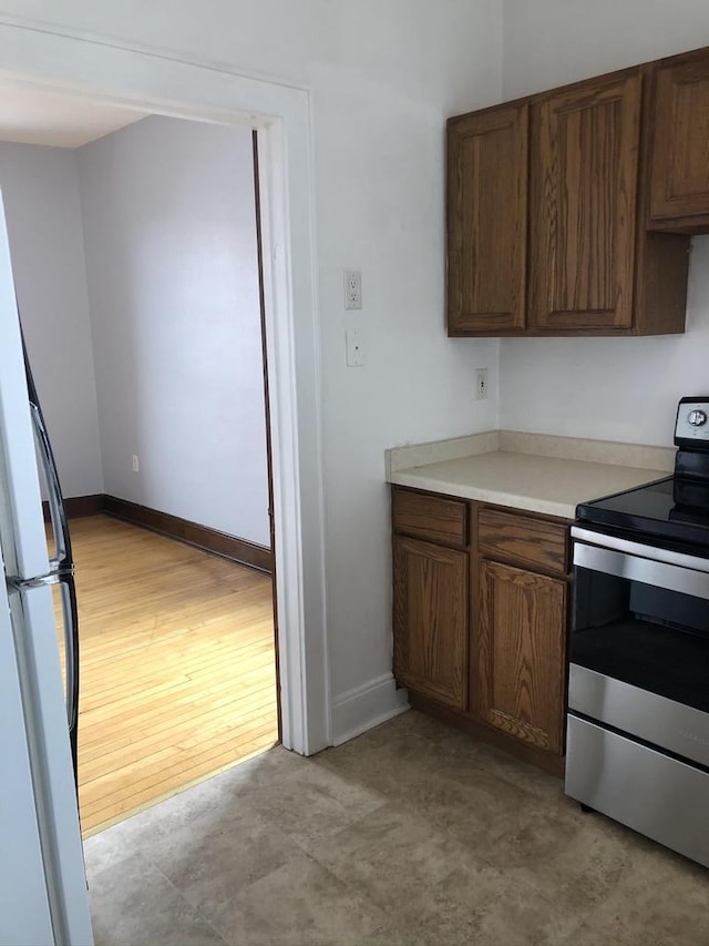 kitchen with white fridge, light hardwood / wood-style floors, and stainless steel range