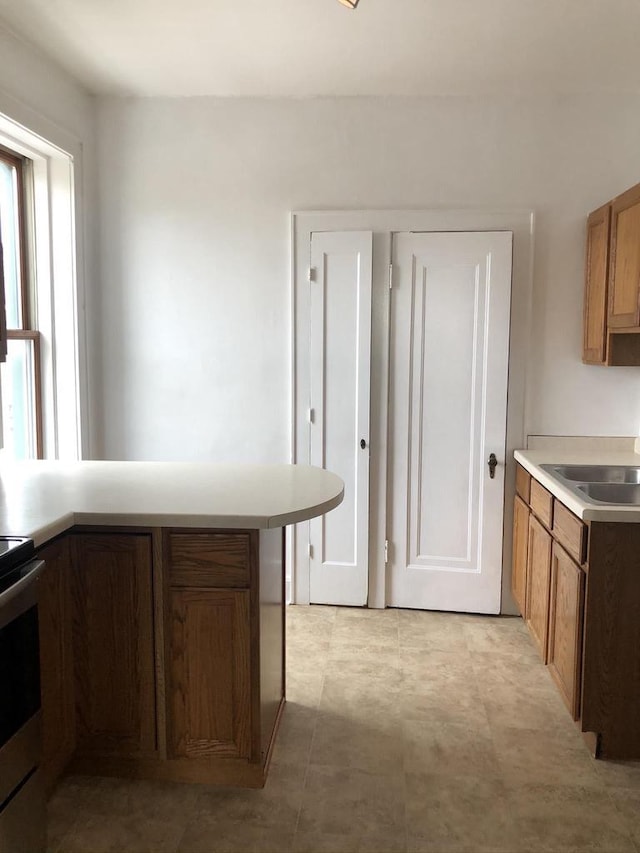 kitchen featuring kitchen peninsula, sink, and stainless steel range oven