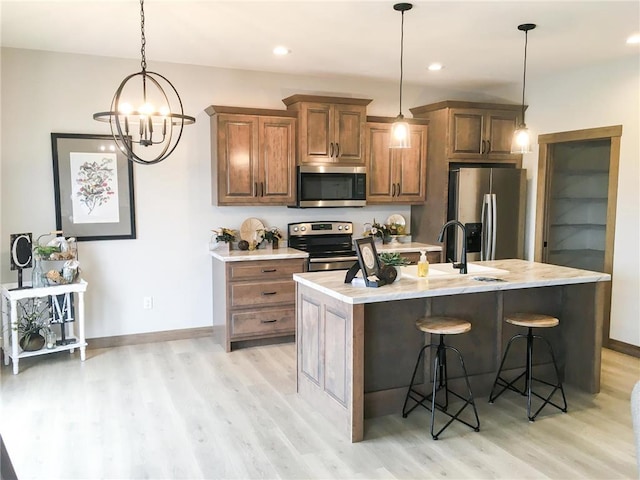 kitchen with light wood-type flooring, stainless steel appliances, a notable chandelier, and sink