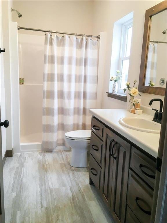 bathroom featuring a shower with curtain, hardwood / wood-style floors, vanity, and toilet