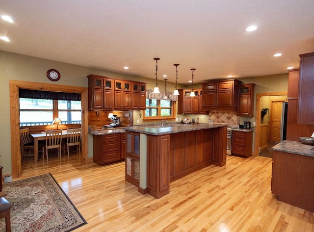 kitchen featuring pendant lighting, decorative backsplash, a kitchen island, and light hardwood / wood-style floors