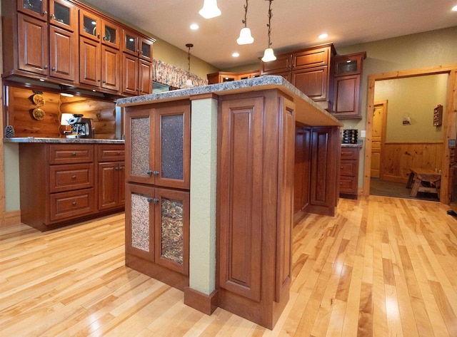 kitchen featuring wood walls, light hardwood / wood-style flooring, and decorative light fixtures