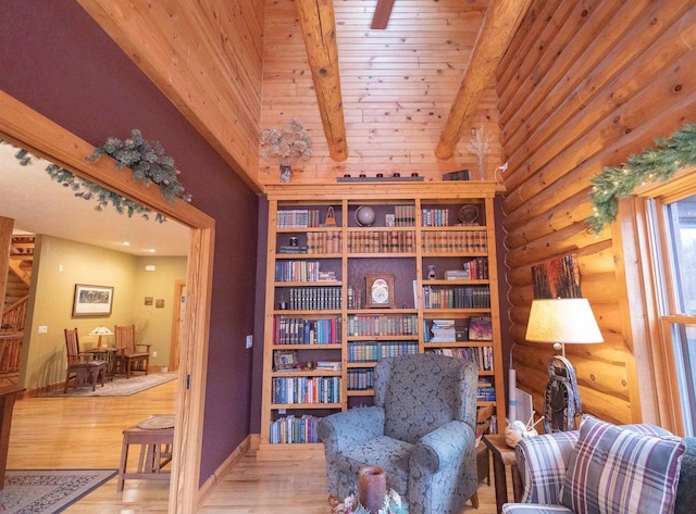 sitting room with hardwood / wood-style floors, lofted ceiling with beams, and rustic walls