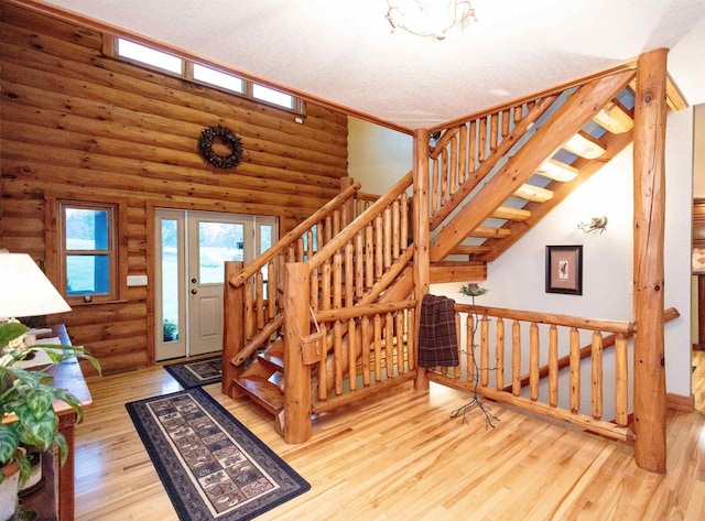 stairs featuring log walls, a textured ceiling, and hardwood / wood-style flooring