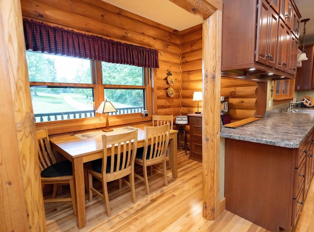 dining room featuring rustic walls, sink, and light wood-type flooring