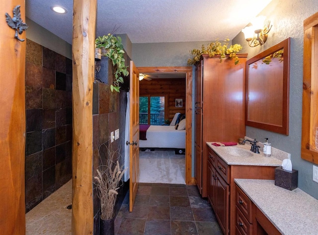 bathroom featuring ceiling fan, a shower, a textured ceiling, and vanity