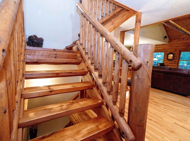 stairway with hardwood / wood-style floors and wood walls