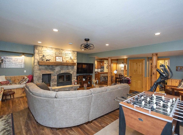 living room with dark hardwood / wood-style flooring and a stone fireplace