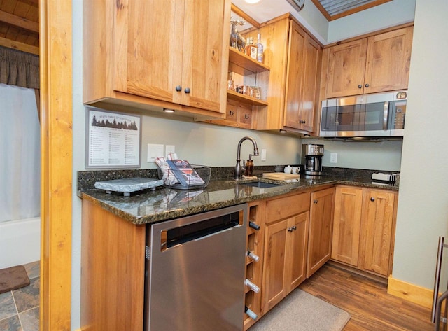 kitchen with sink, stainless steel appliances, dark stone counters, and dark wood-type flooring