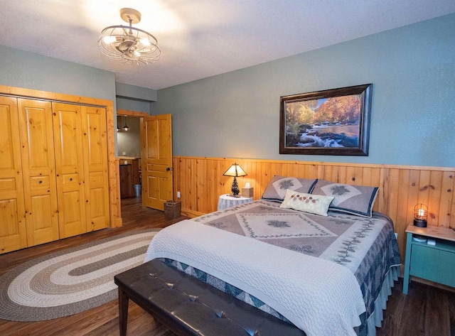 bedroom featuring a closet, dark hardwood / wood-style flooring, and wooden walls