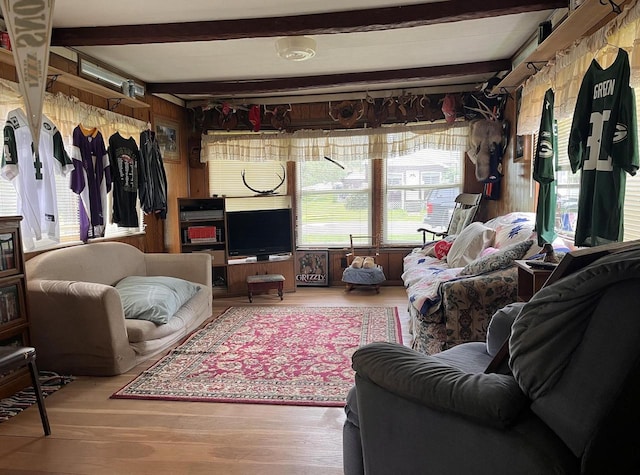 living room featuring beamed ceiling, wood-type flooring, and wood walls