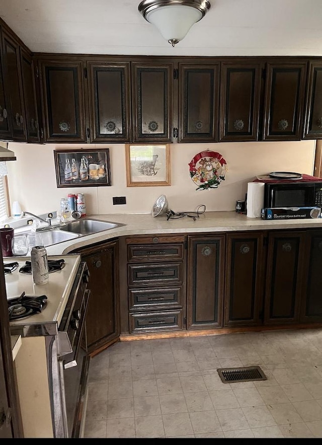 kitchen with sink, dark brown cabinetry, and white stove