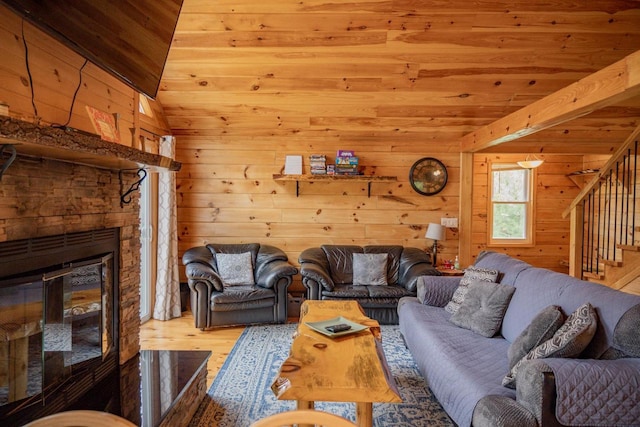 living room with light wood-type flooring, wood ceiling, vaulted ceiling, a stone fireplace, and wood walls