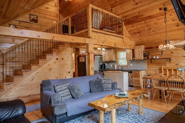 living room with a high ceiling, light hardwood / wood-style floors, wooden walls, and sink