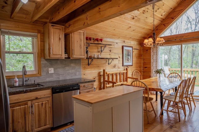 kitchen with stainless steel dishwasher, plenty of natural light, sink, and wooden walls