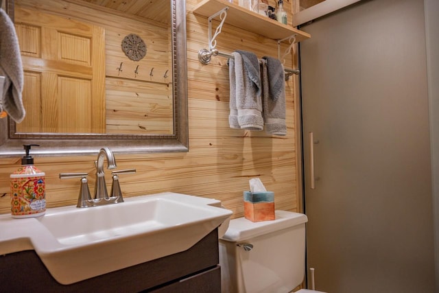 bathroom featuring vanity, toilet, and wooden walls