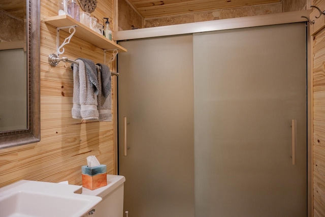 bathroom featuring toilet, walk in shower, and wooden walls