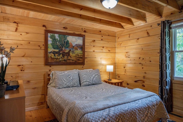 bedroom with beamed ceiling, wood-type flooring, and wooden walls