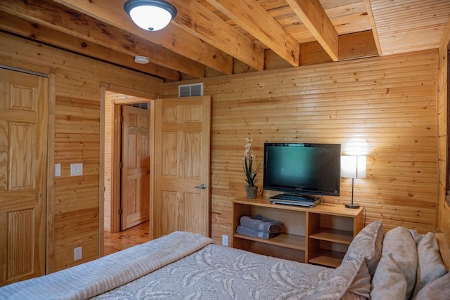 bedroom with beam ceiling, wood ceiling, and wood walls